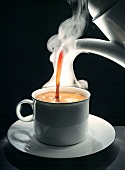Kaffee wird in Tasse gegossen, schwarzer Hintergrund