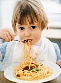 Kleines Mädchen isst Spaghetti mit Tomatensauce