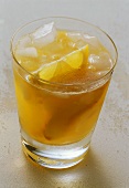 Nectarine drink with ice and wedge of lemon in glass