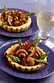 Two ham and mushrooms tartlets with green asparagus