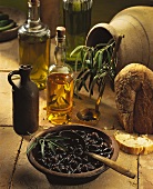 Stillleben mit eingelegten schwarzen Oliven, Olivenöl und Brot