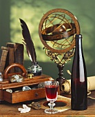 Flasche und Glas Rotwein, auf Schreibtisch vor antikem Globus