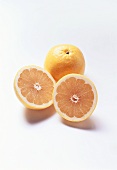 Two grapefruit halves in front of whole yellow grapefruit