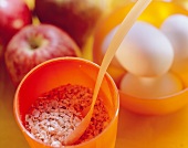 Oats in mug, apples and white eggs behind