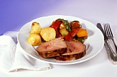Two slices of rolled roast pork with potatoes, peppers