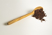 Cocoa powder falling from a wooden spoon on to a surface