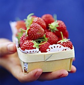 Hand holding small bowl of strawberries