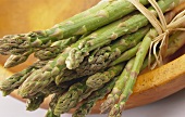 A bundle of green asparagus in a wooden bowl