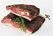 Two pieces of Tyrolean schinkenspeck & a sprig of rosemary