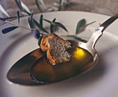 Piece of bread in olive oil on spoon