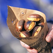 Hand holding paper bag with chestnuts