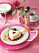 Panna cotta heart with puff pastry arrow on red fruit sauce