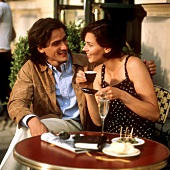 Junges Paar am Tisch eines Cafes mit Oliven, Sekt, Kaffee