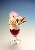 Ice cream sundae with strawberry sauce, cream & wafer rolls