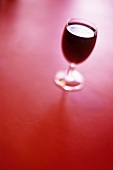 A glass of red wine against red background
