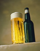 Kaltes Bier in hohem Glas vor Bierflasche