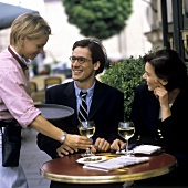 Kellnerin serviert einem Paar Wein in Restaurant im Freien