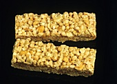 Two muesli bars with nuts against black backdrop