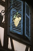 Weintraubenschild an einem Haus in Riquewihr (Elsass)