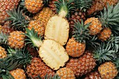 Many pineapples, one halved (filling the picture)