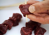 Threading diced kangaroo meat on to skewers