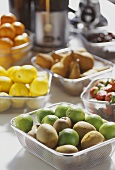 Various fruits for juice, with juicer behind