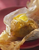 Baked potato with butter on paper