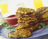 Corn pancakes in a pile, with sauce in bowl