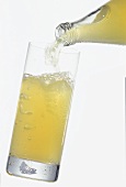 Pouring naturally cloudy apple juice drink into a glass
