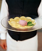 Waitress carrying plate of ice cream on nectarine carpaccio