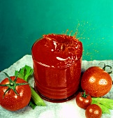 Tomato juice splashing out of glass, fresh tomatoes beside it