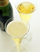Two filled champagne flutes, champagne bottle behind
