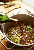 Pouring red wine on to spring onions