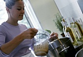 Young woman pouring stock into soup pan