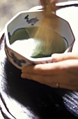 Grünen Tee mit Bambusbesen umrühren