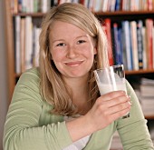Blond woman with a glass of milk and milk round her mouth