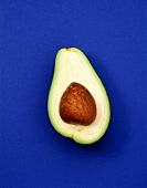Half an avocado with stone on blue background