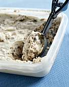 Ice cream with cake crumbs in container with ice cream scoop