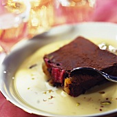 A piece of chocolate cake on custard with spoon