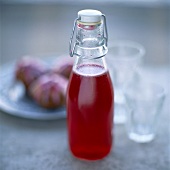 A bottle of cranberry juice, cranberry muffins behind