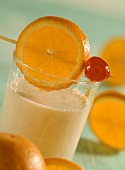 Bananenmilchshake mit Orangenscheibe und Cocktailkirsche