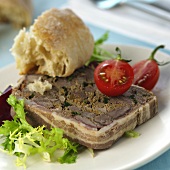 A slice of game terrine with bread and tomatoes