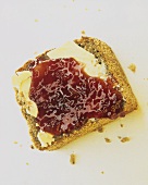 A slice of bread with butter and strawberry jam