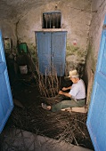 Old man weaving basket from thin branches, Santorini