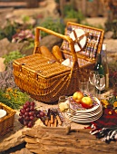 Still life with picnic basket, crockery, glasses and wine