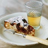 A piece of plum cake and a glass of apple juice