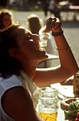 Young woman in a Bavarian beer garden eating radishes