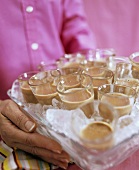 Hands holding tray with glasses of ice-cold chocolate liqueur