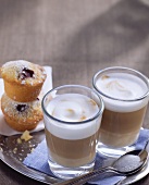 Two glasses of latte macchiato and muffins on a tray
