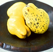 Three quinces in a wooden bowl